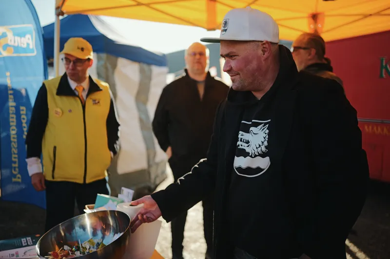 Joona Vainio valkoisessa lippalakissa ojentaa makeiskulhoa.
