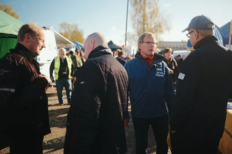 Jorma Piisinen keskustelemassa pienessä ryhmässä teltan vieressä.