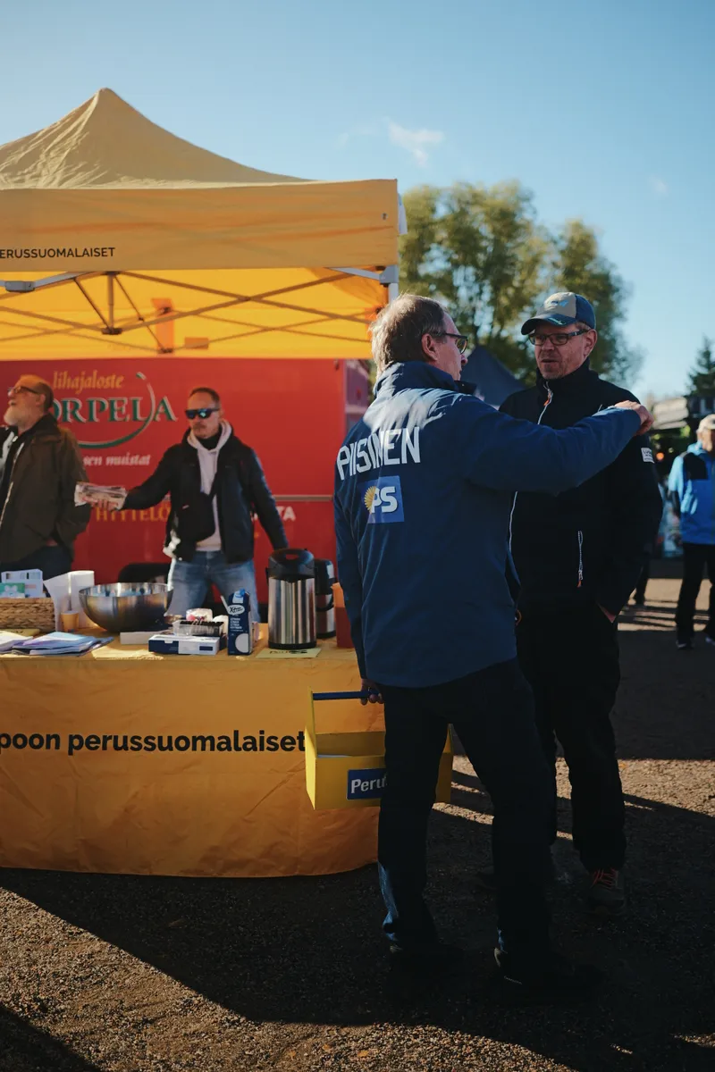 Kaksi markkinakävijää yhteiskuvassa keltaisen teltan edessä.
