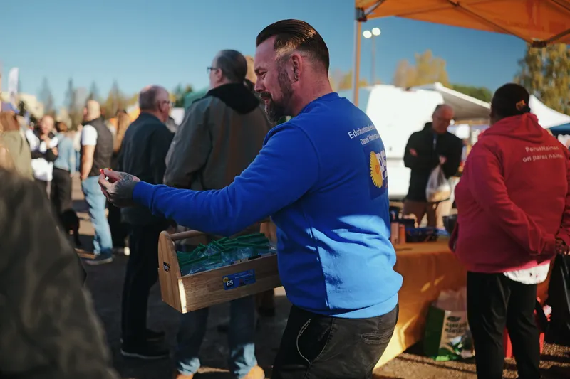 Daniel Hindersson sinisessä paidassa, kantolaatikko kädessään.